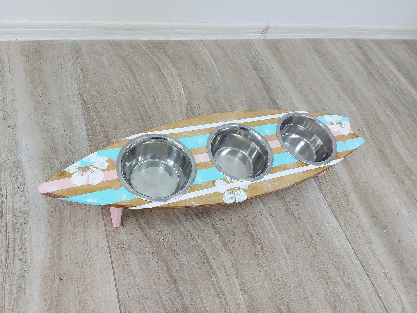 Wooden surfboard‑shaped feeding station with stainless bowls