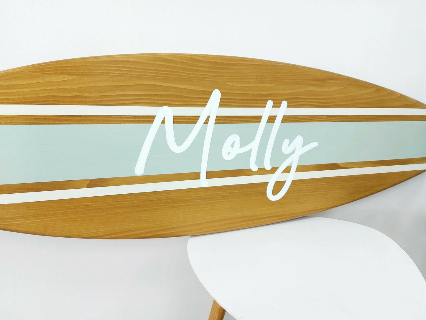 Wooden surfboard-shaped table with 'Molly' branding on a white background