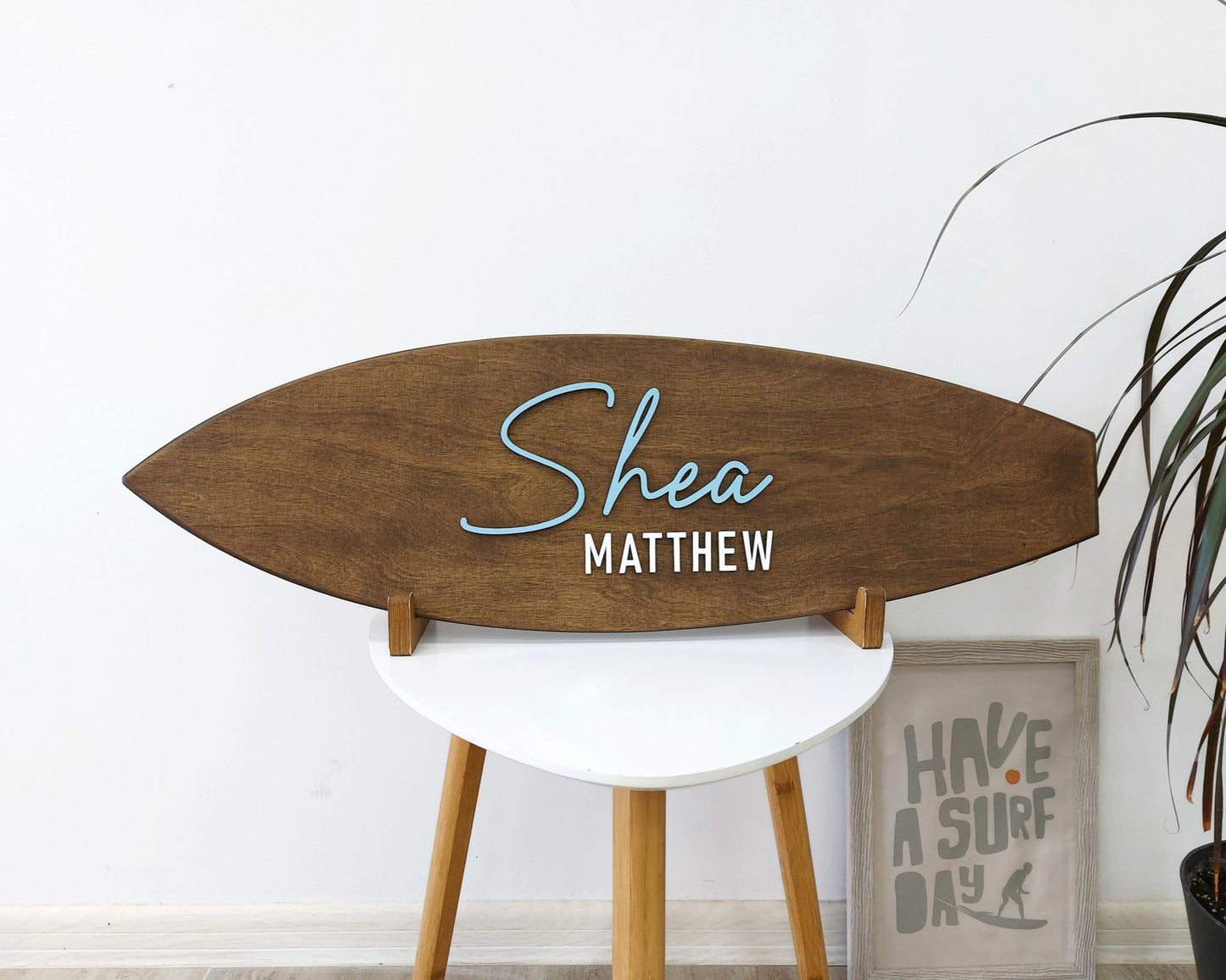 Personalized surfboard baby name sign hanging above crib in beach-themed nursery