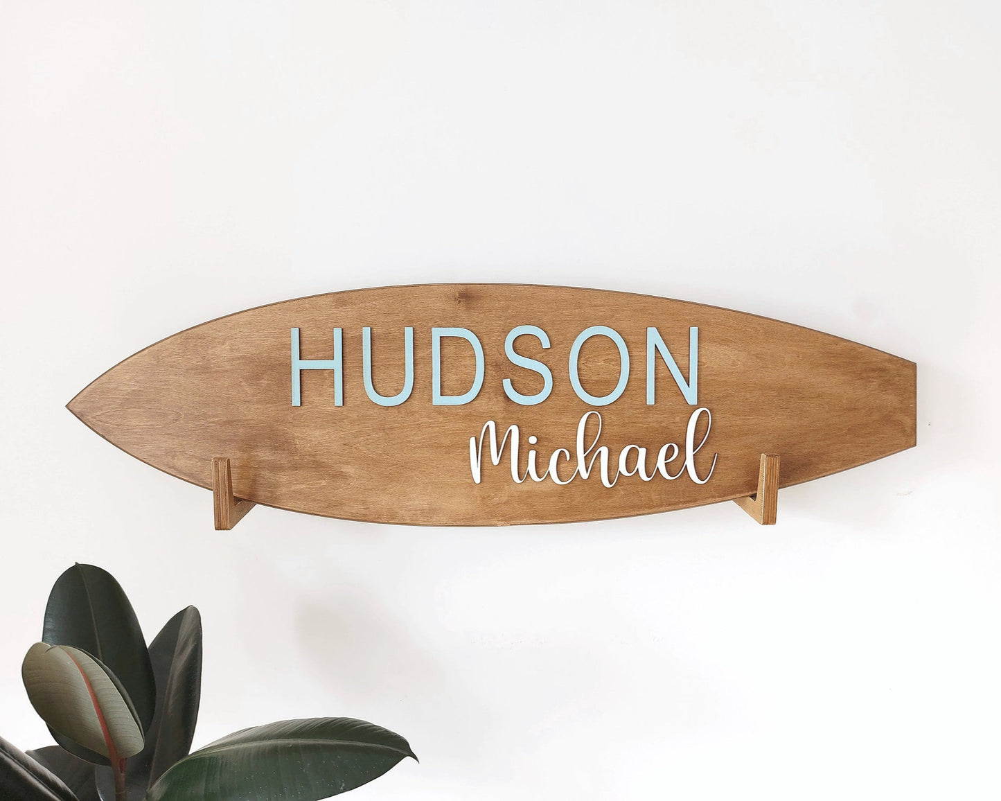 Personalized baby name surfboard sign hanging in coastal-style nursery