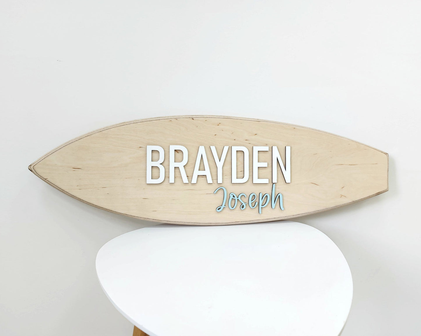 Personalized wooden surfboard sign with raised 3D letters on wall