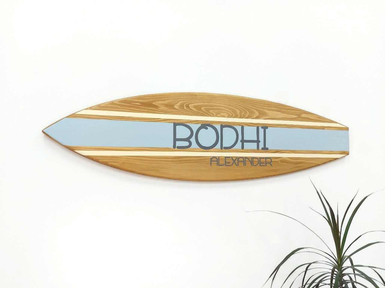 Wooden surfboard-shaped wall art with 'Bodhi' branding on a white background