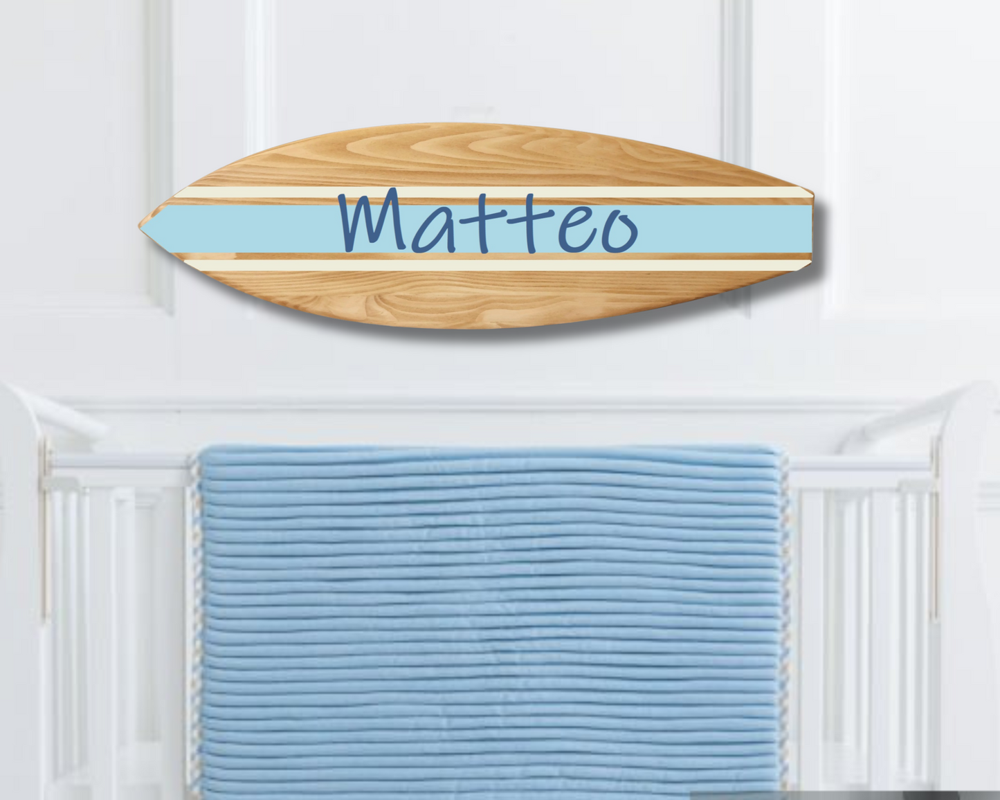 Wooden surfboard name sign hanging above crib in beach-themed nursery