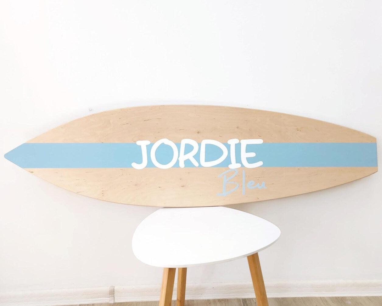 Wooden personalized surfboard baby name sign hanging in nursery