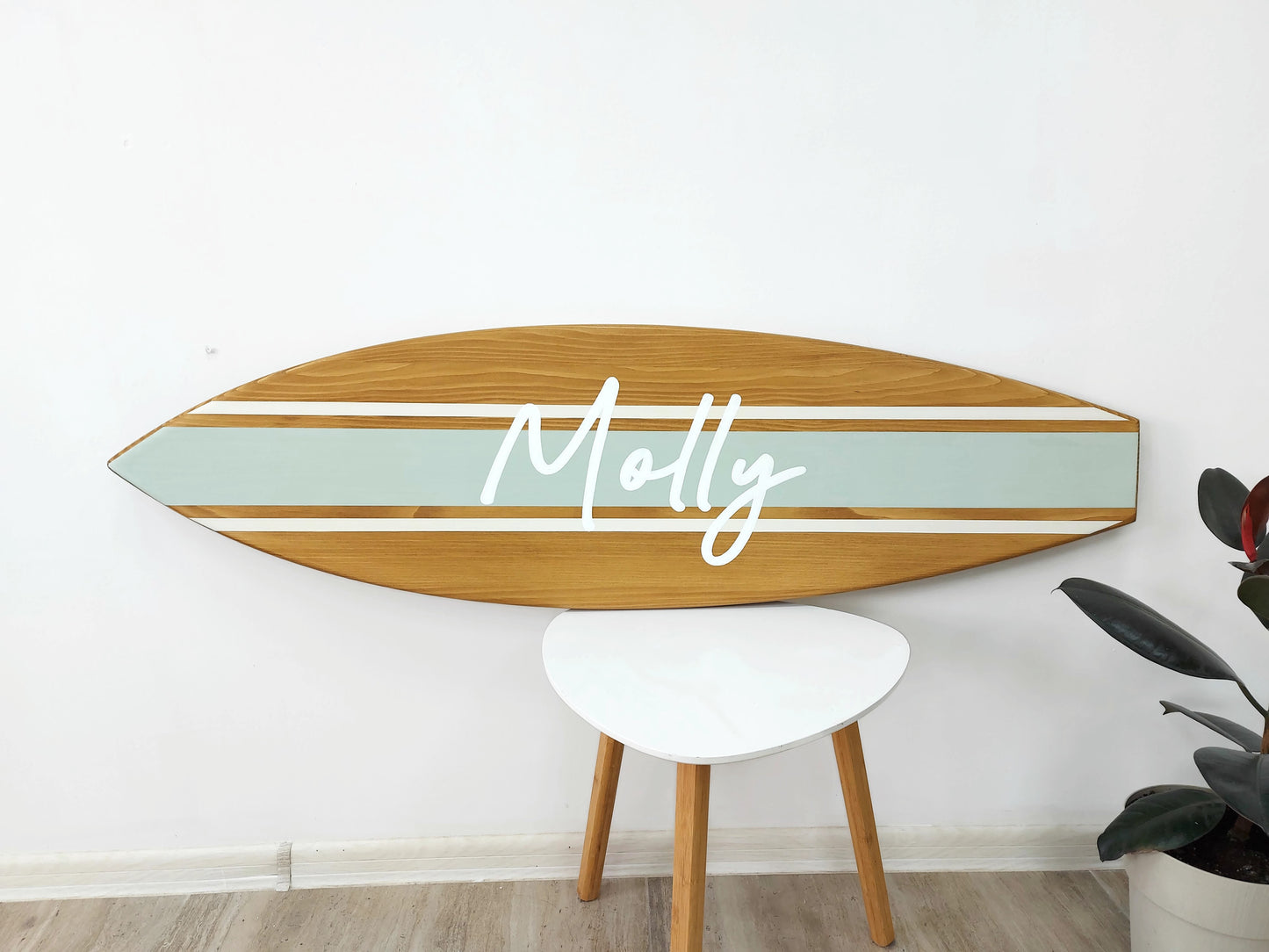 Coastal-style wall art shaped like a surfboard with engraved name