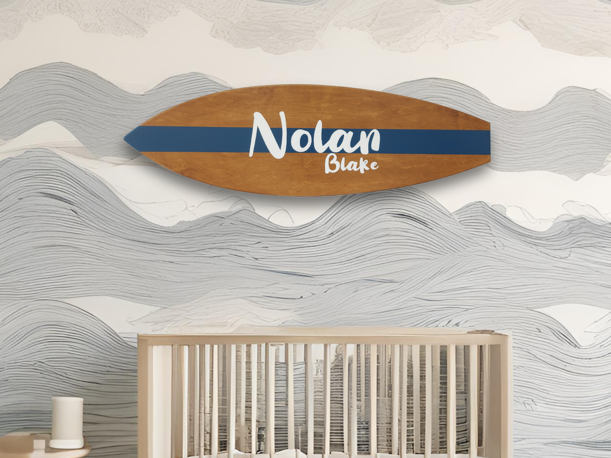 Wooden surfboard with baby name, mounted on a wall above a crib.