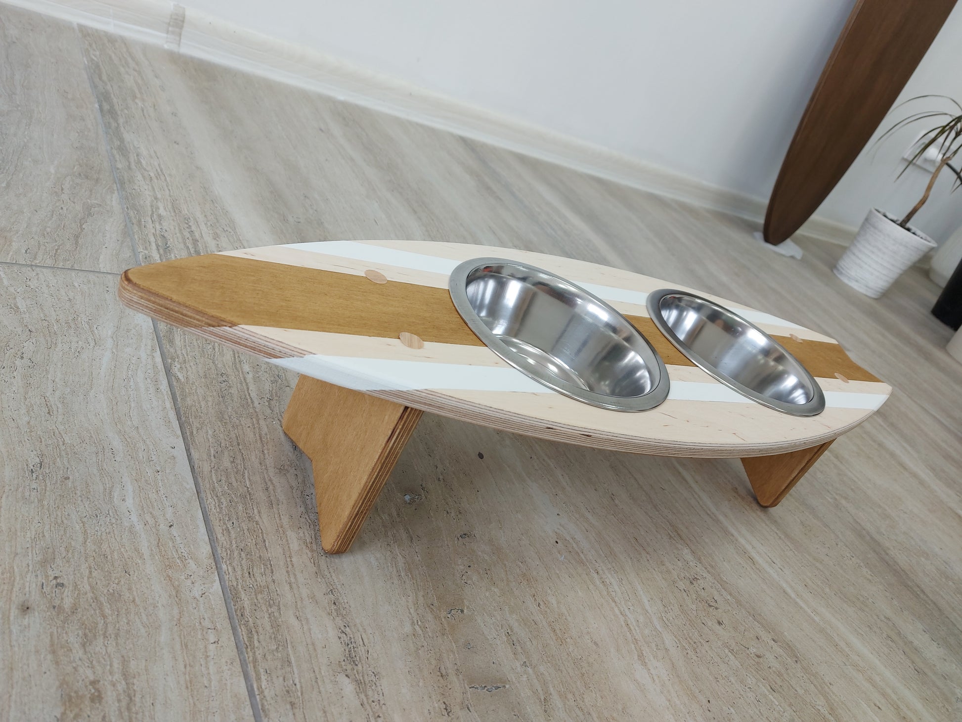 Wooden surfboard feeding station for pets holding stainless steel bowls