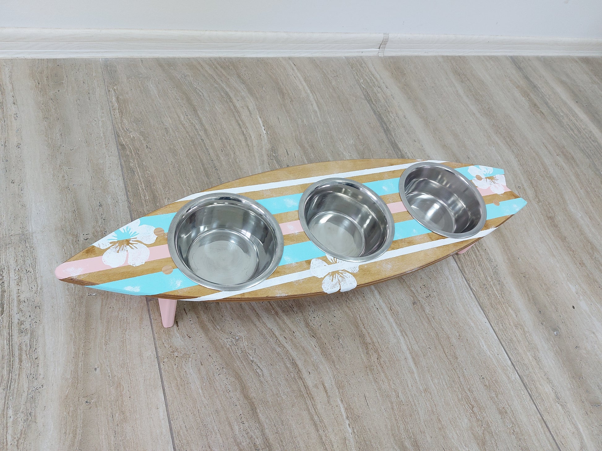 Wooden surfboard‑shaped feeding station with stainless bowls
