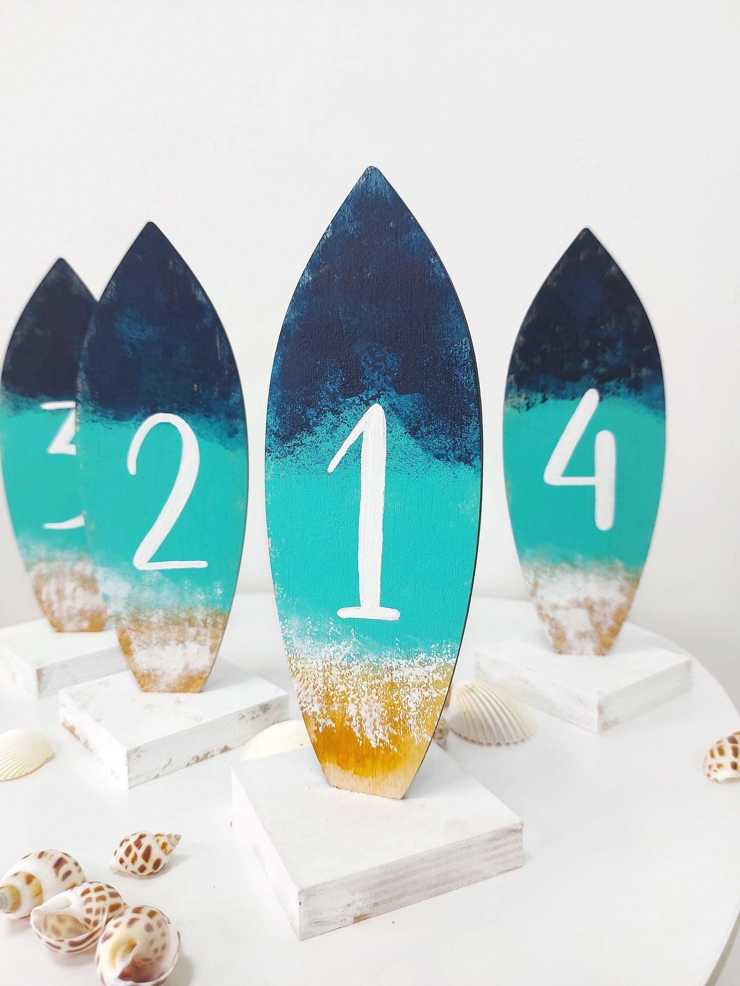 Ocean themed surfboard wedding table number displayed on beach table