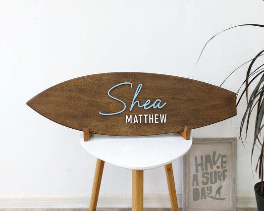 Personalized surfboard baby name sign hanging above crib in beach-themed nursery