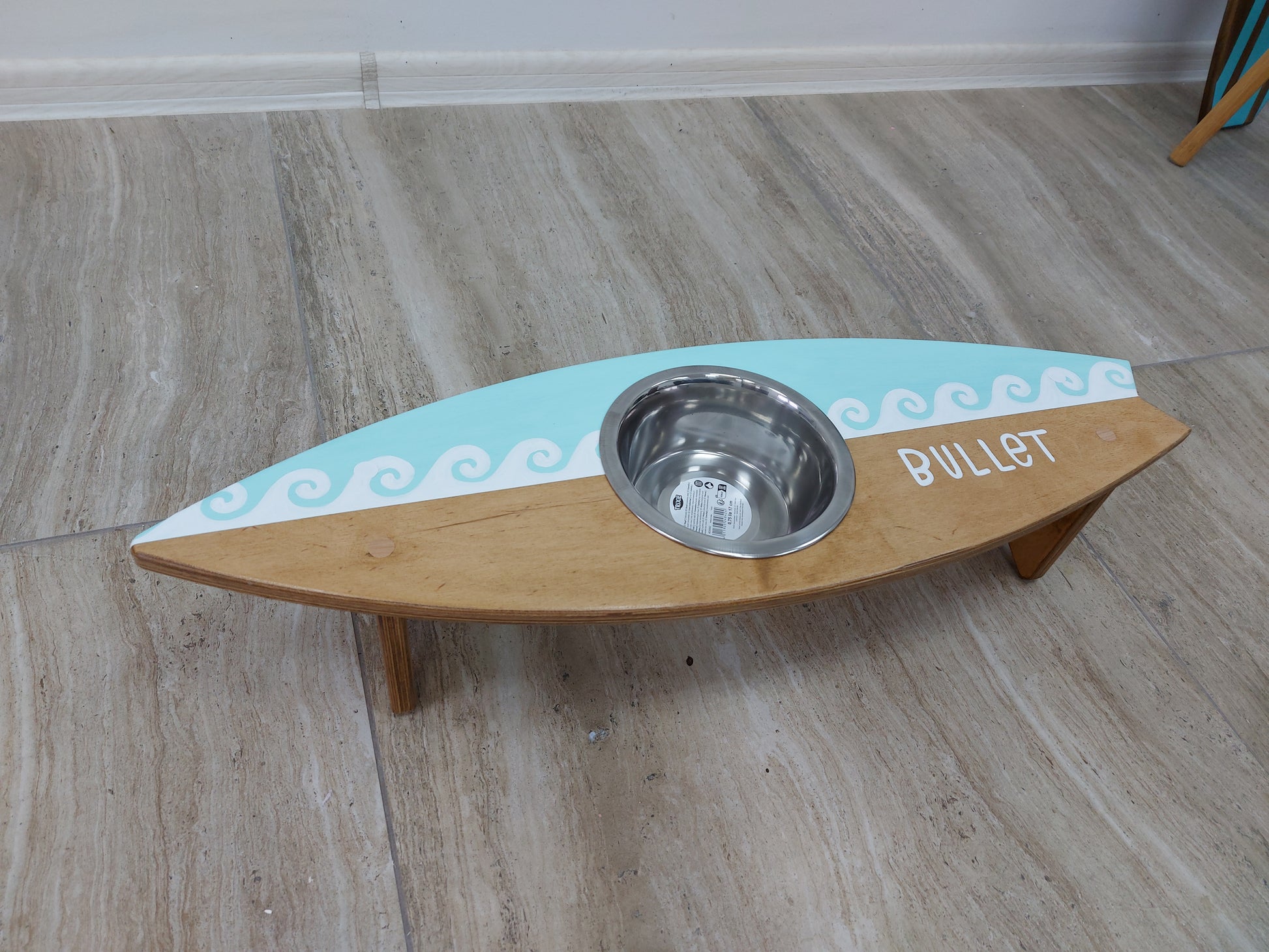 Close-up of painted name on custom surfboard dog feeding stand