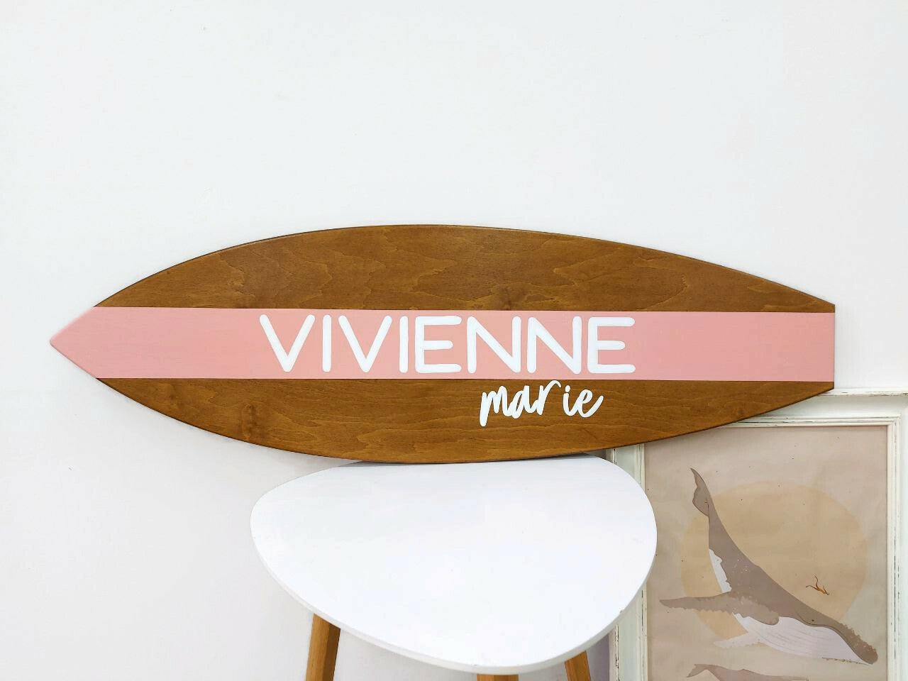 Surfboard-shaped wood name sign with natural finish in coastal interior