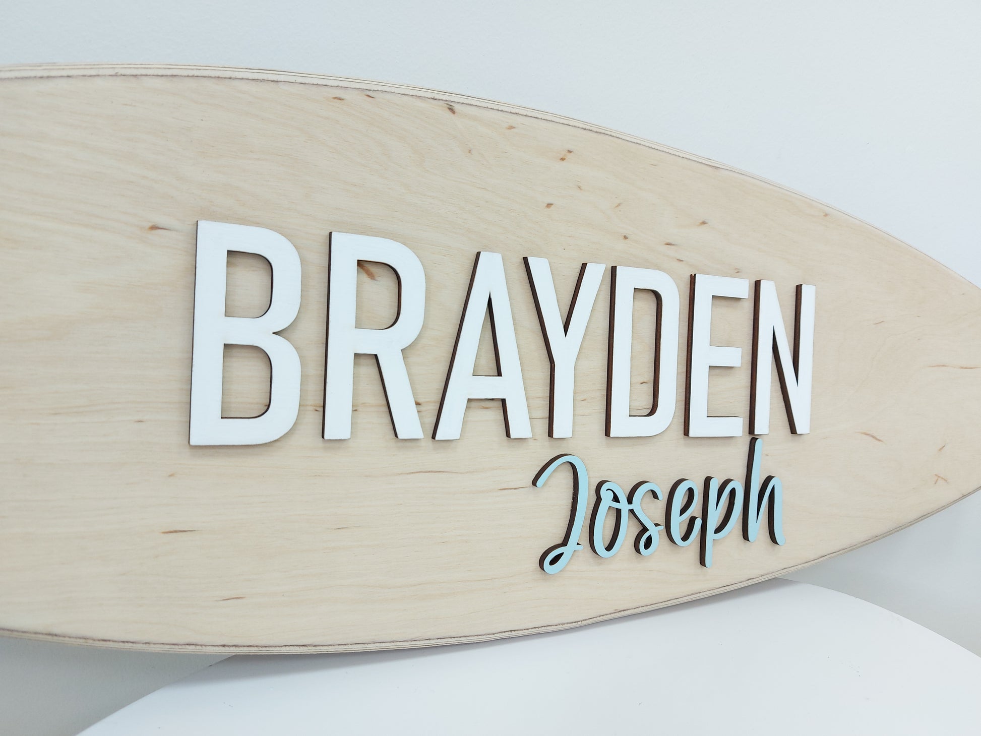 Artisan-made wooden surfboard sign with name in dimensional style
