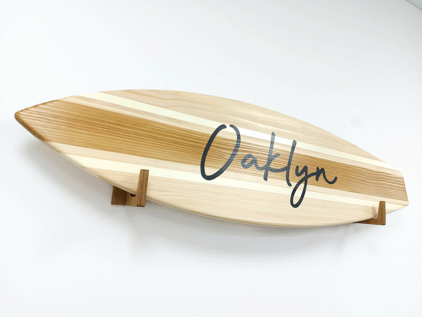 Wooden surfboard-shaped wall art with 'Oaklyn' branding on a white background