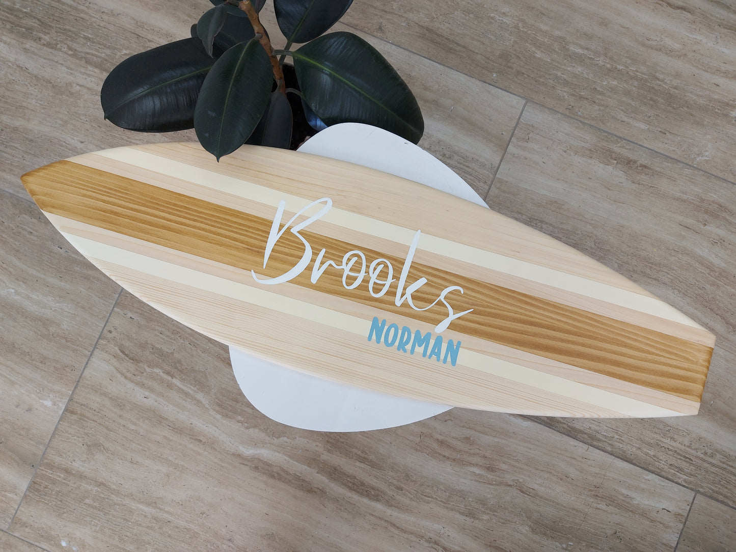 Wooden surfboard with 'Brooks Norman' branding on a wooden floor.