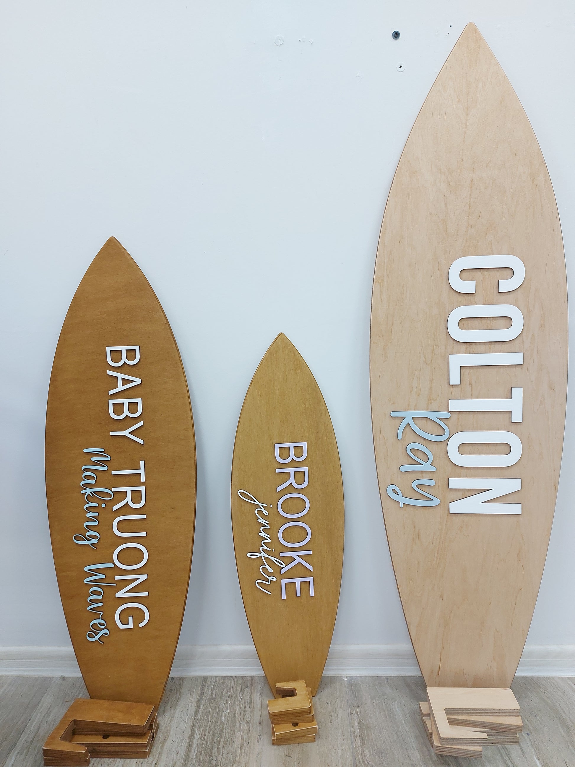 Wooden surfboard-shaped signs with names on a white wall