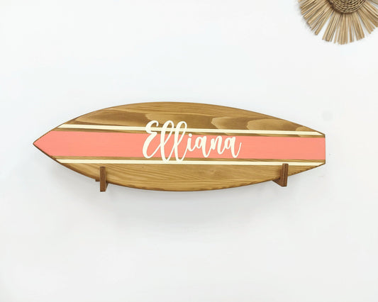 Wooden name sign hanging above crib in beach-themed nursery