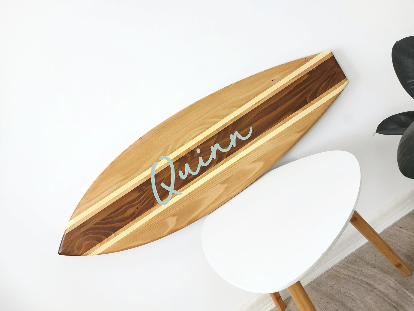 Surfboard wall sign with baby’s name above crib in pastel room