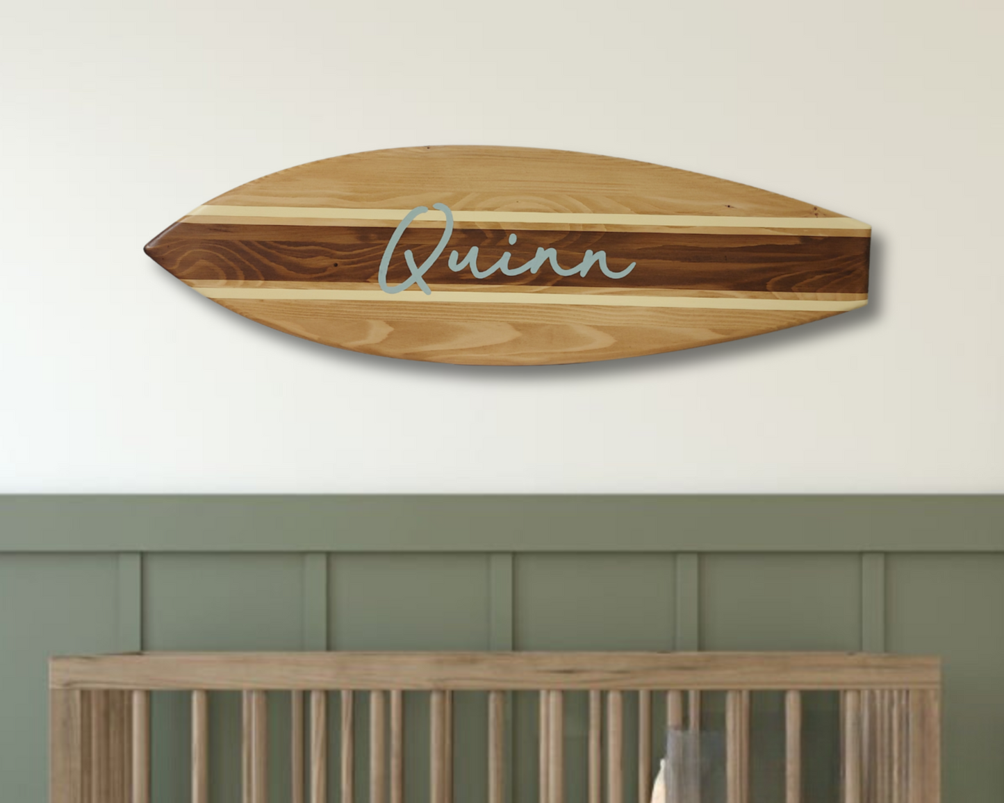 Personalized wooden name sign hanging above baby crib in nursery