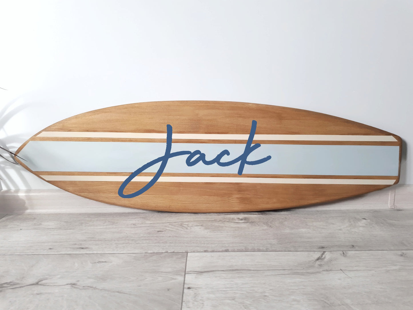 Close-up of engraved name on handcrafted wooden surfboard