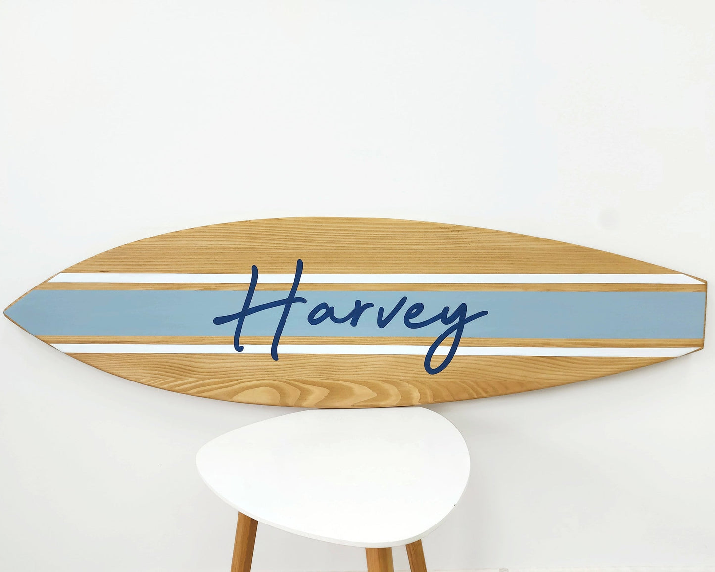 Personalized wooden surfboard wall sign hanging in beach-themed room