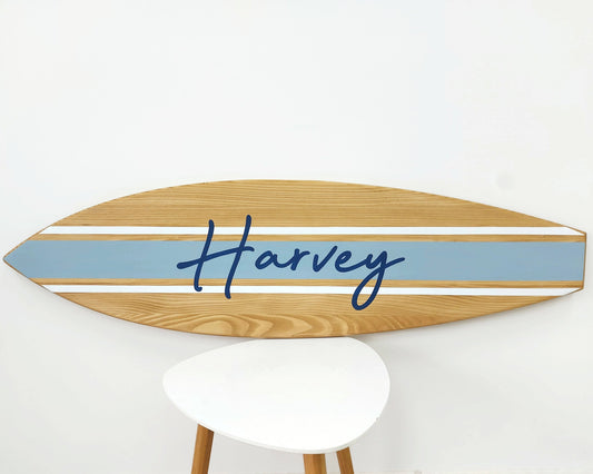 Personalized wooden surfboard wall sign hanging in beach-themed room