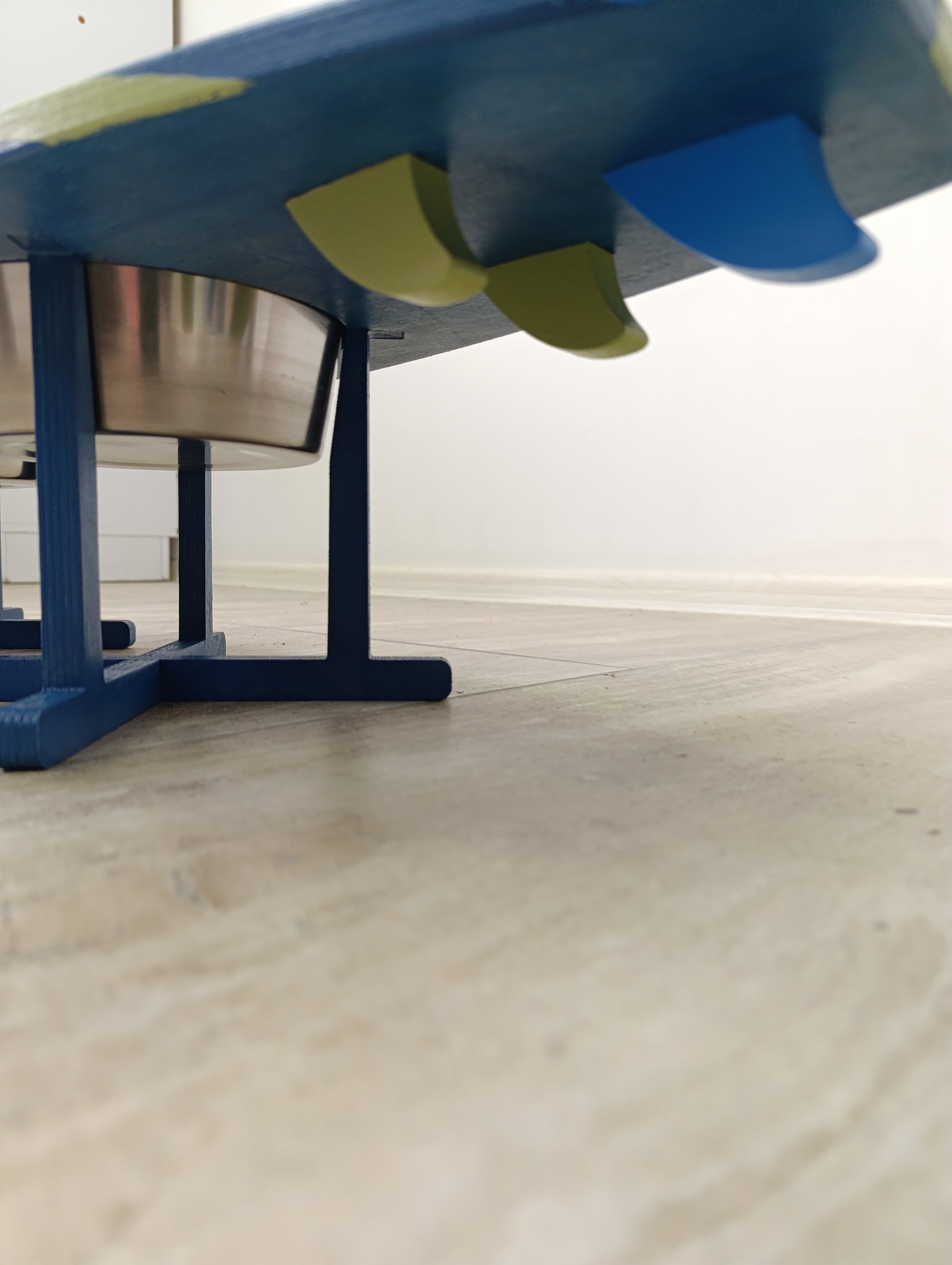 Close-up of special surfboard decor elements on pet feeder stand on a wooden surface