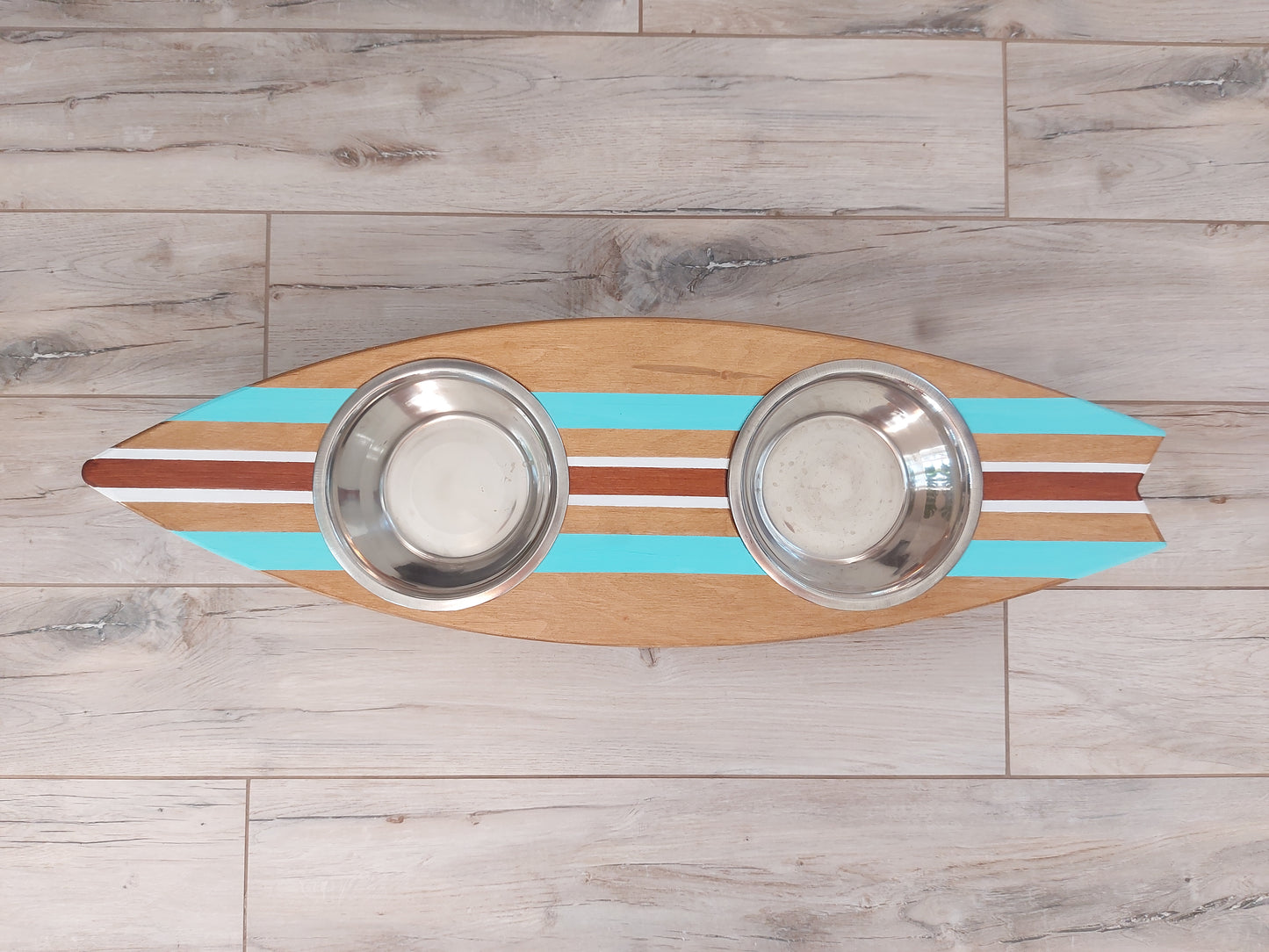 Surfboard-shaped dog bowl holder styled in coastal home decor