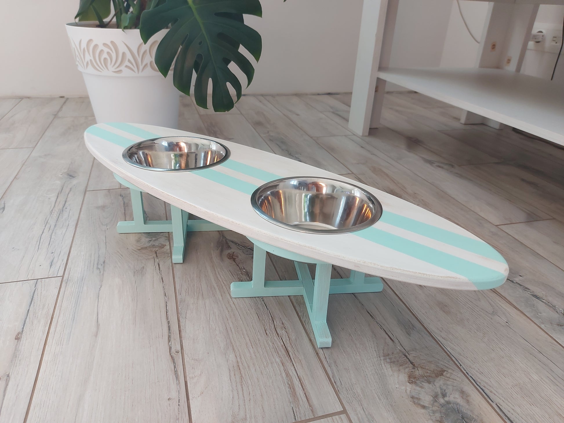 Dual bowl surfboard stand holding food bowls in coastal setting