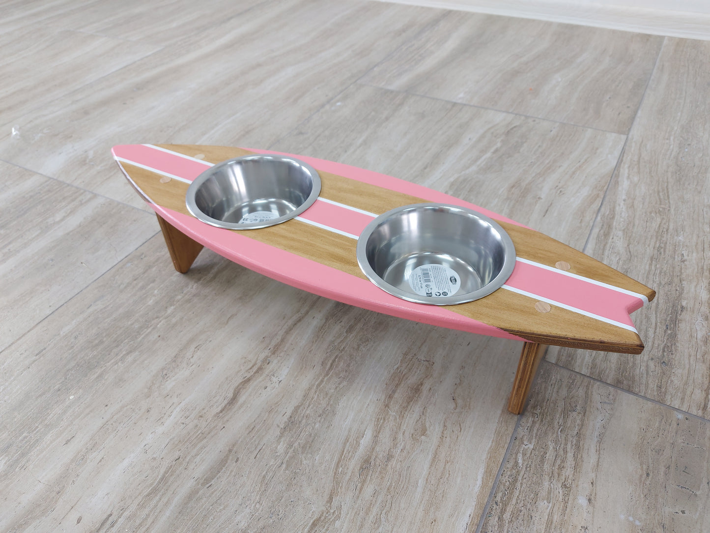 Custom wooden surfboard bowl holder placed on floor with food and water