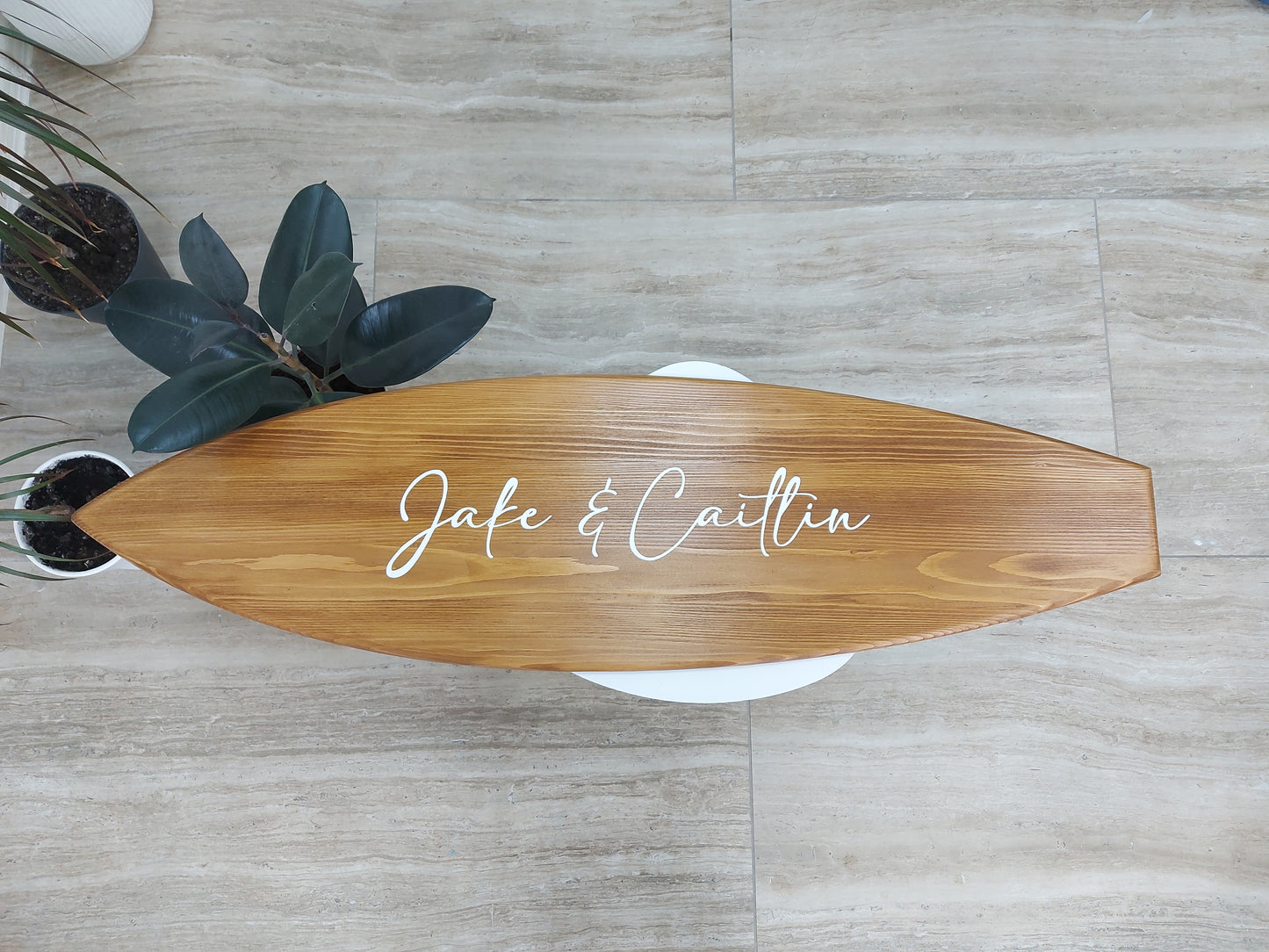 Guests signing surfboard wedding sign alternative at seaside ceremony