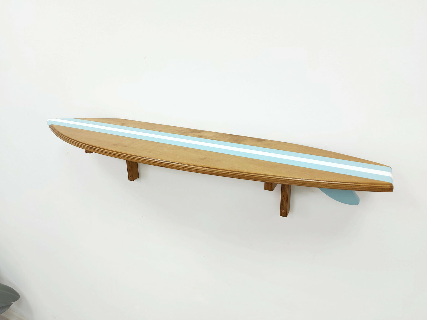 Wooden shelf designed to look like a surfboard with blue stripes on a white wall.