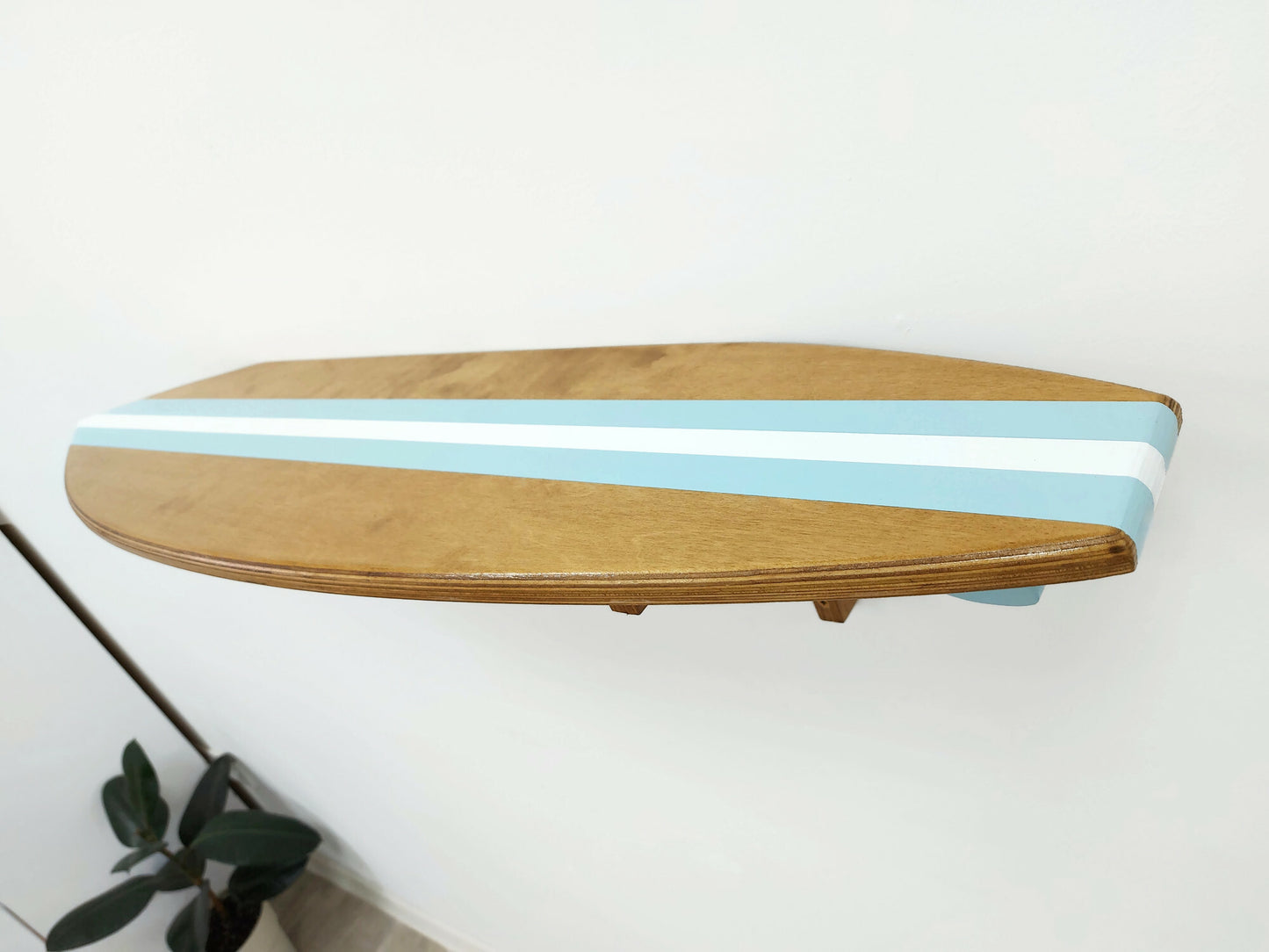 Wooden surfboard shelf with blue stripes on a white wall
