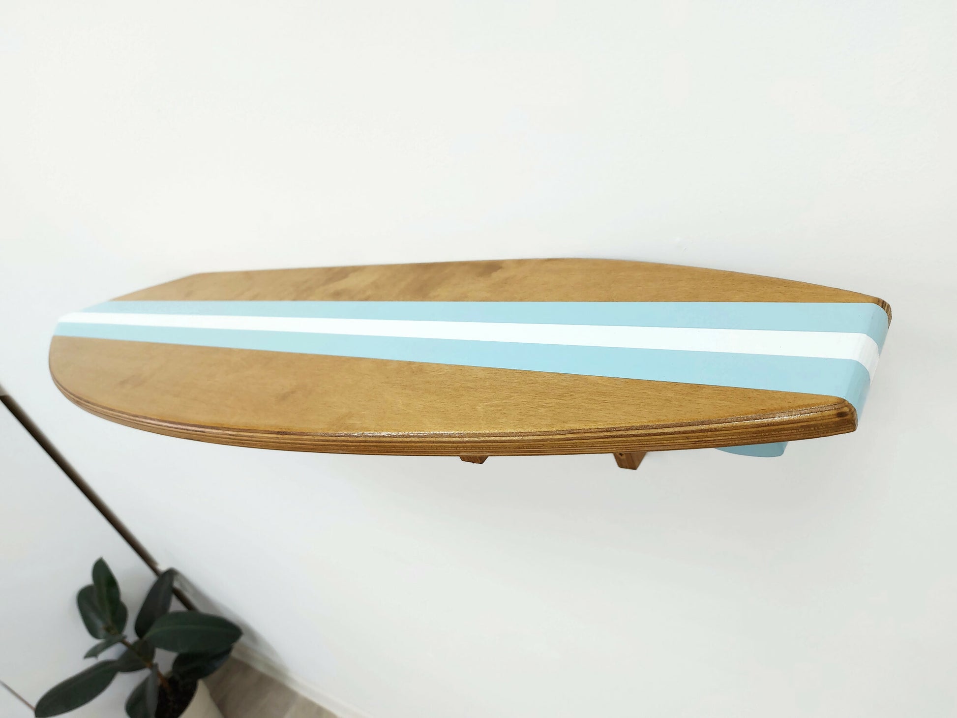 Wooden surfboard shelf with blue stripes on a white wall