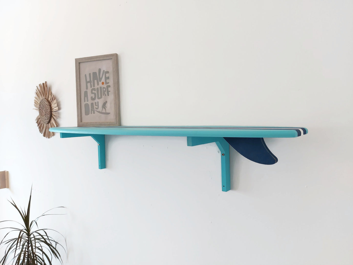 Blue surfboard shelf with a framed picture on a white wall