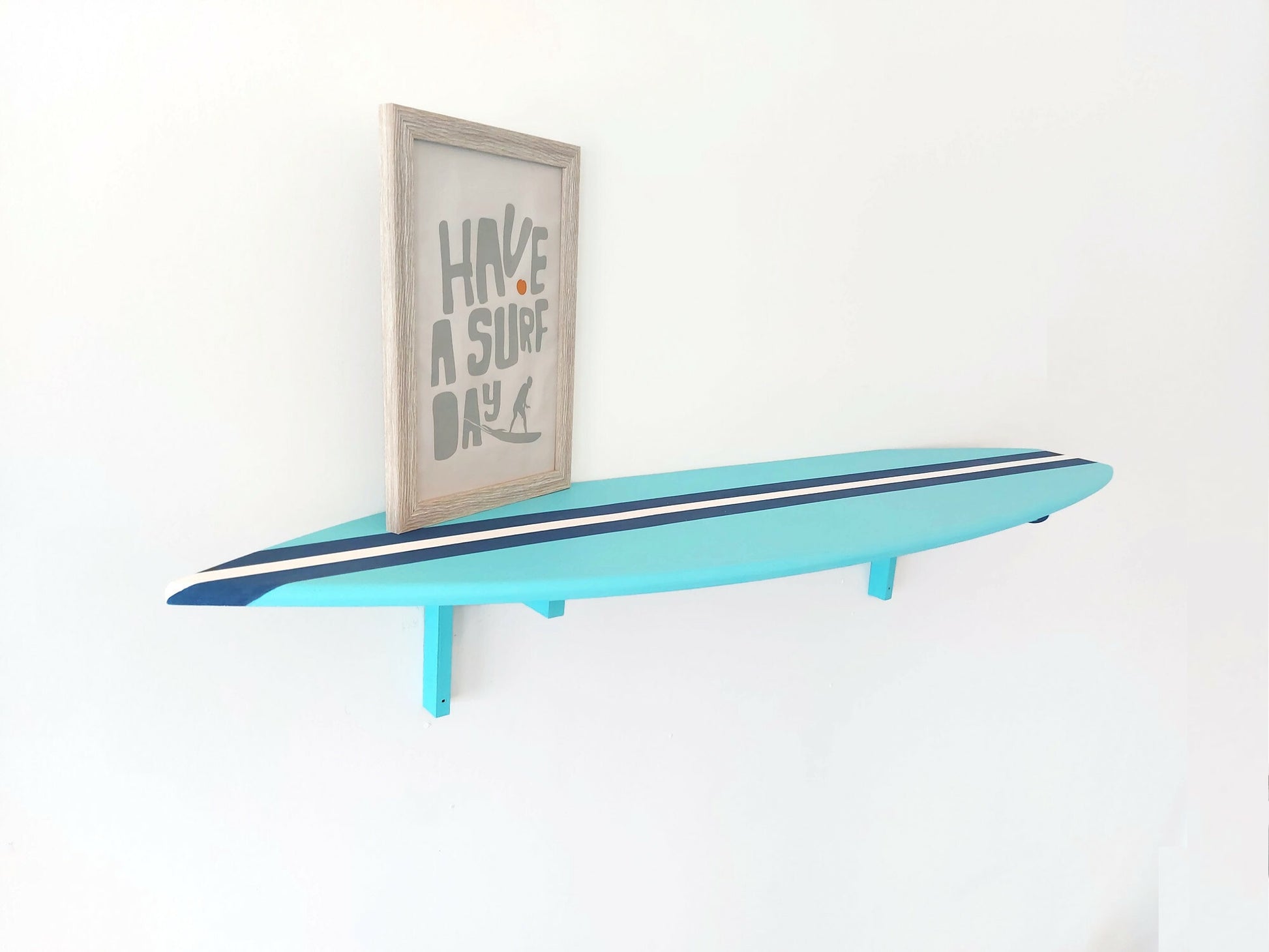 Turquoise surfboard-shaped shelf with a framed picture on a white wall