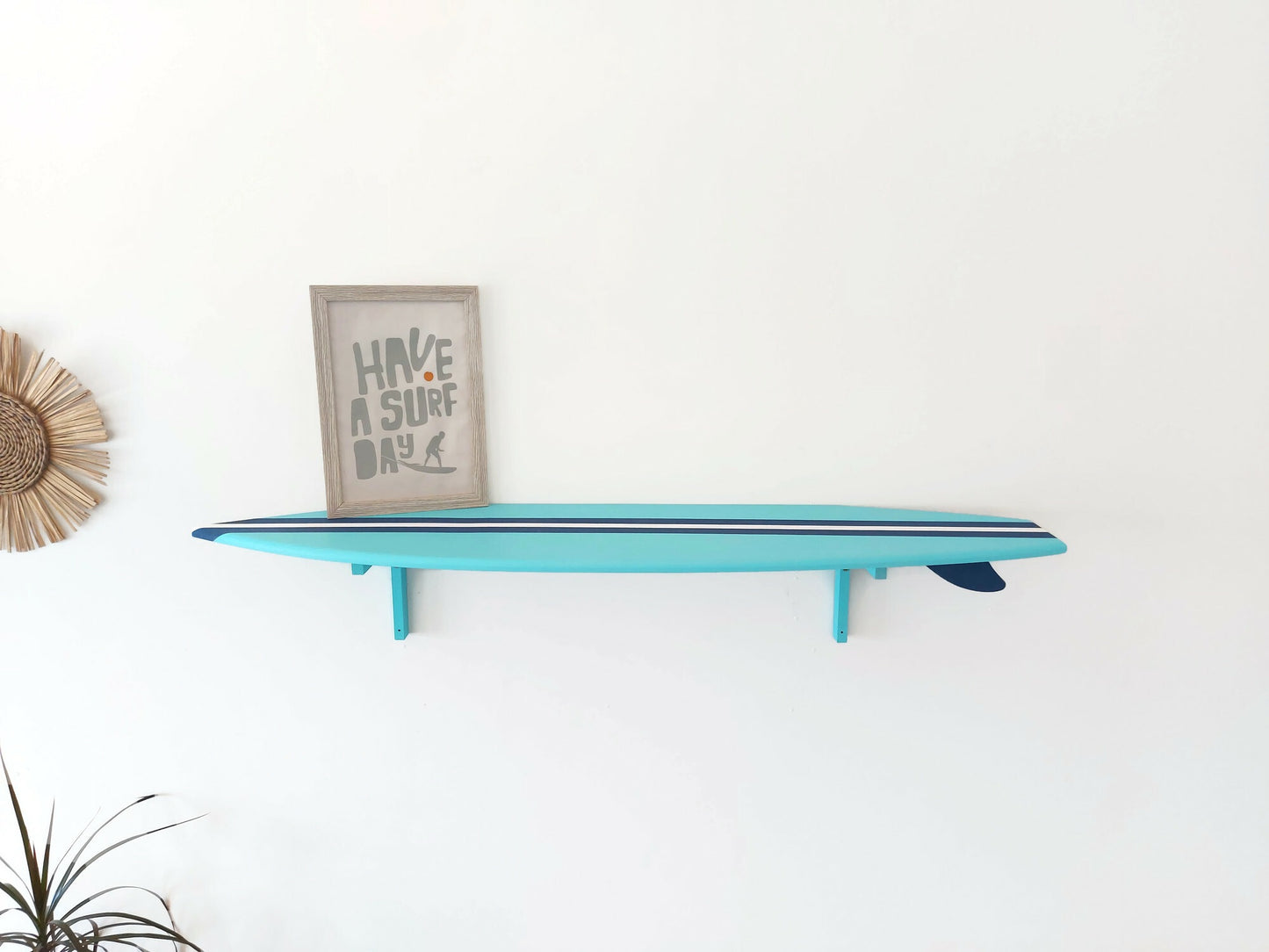 Turquoise surfboard shelf with a framed picture on a white wall
