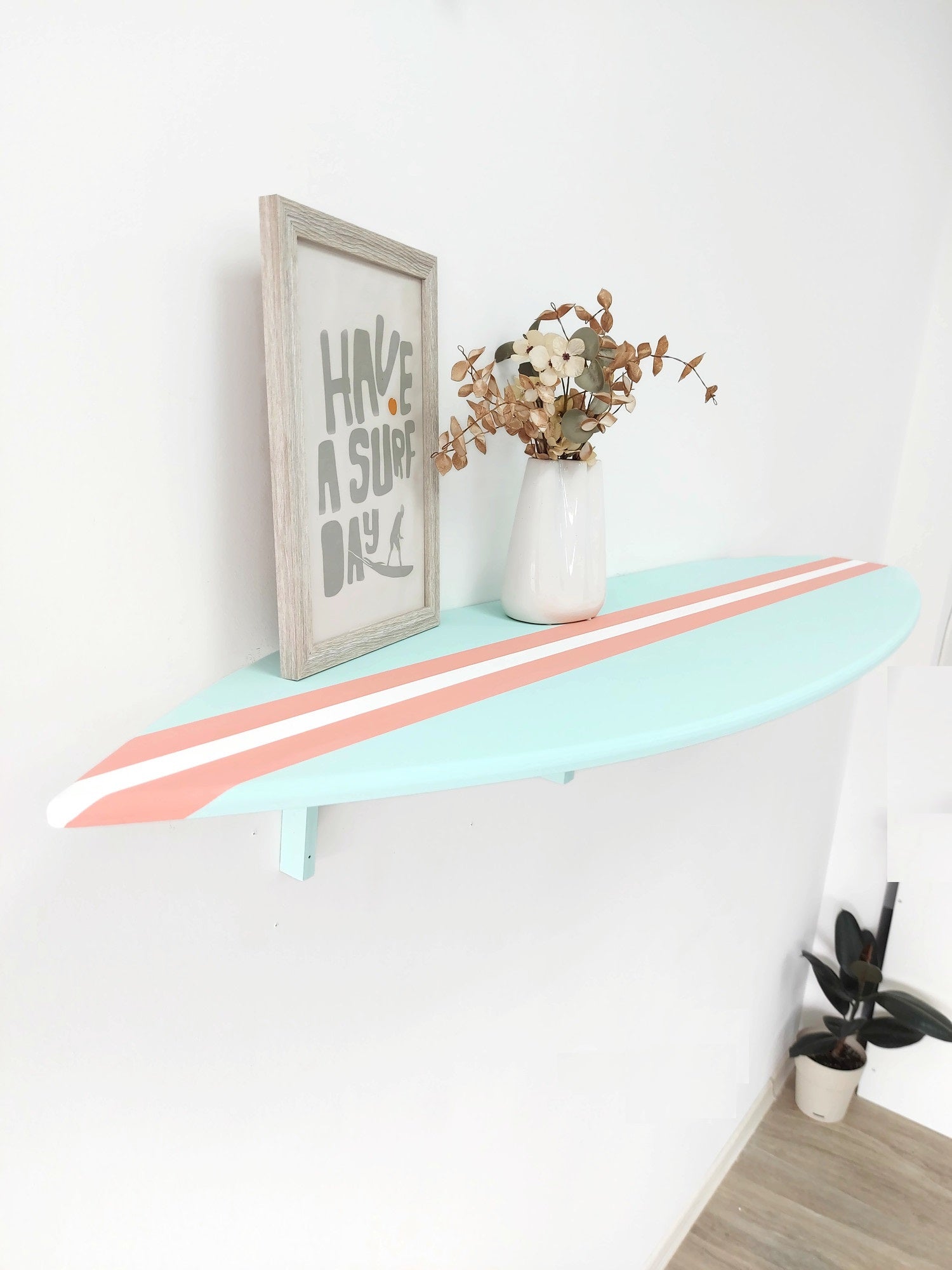 Surfboard wall shelf with decorative elements on a white wall