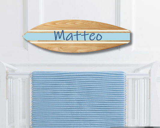 Wooden surfboard name sign hanging above crib in beach-themed nursery
