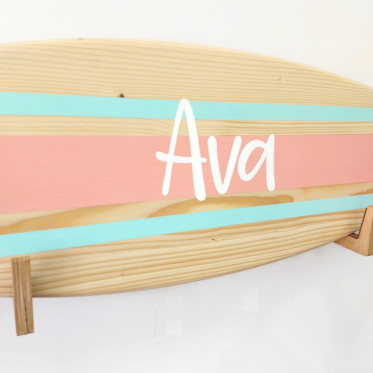 Close-up of personalized engraved name on wooden surfboard decor