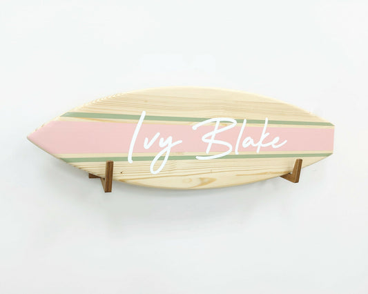 Decorative wooden surfboard name sign hanging in nursery or kids' room