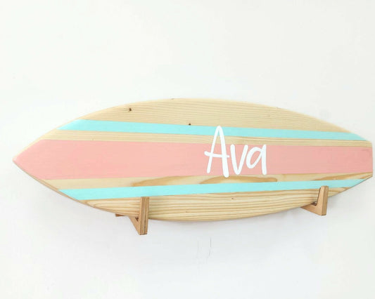 Wooden personalized surfboard name sign hanging on wall in kids' room
