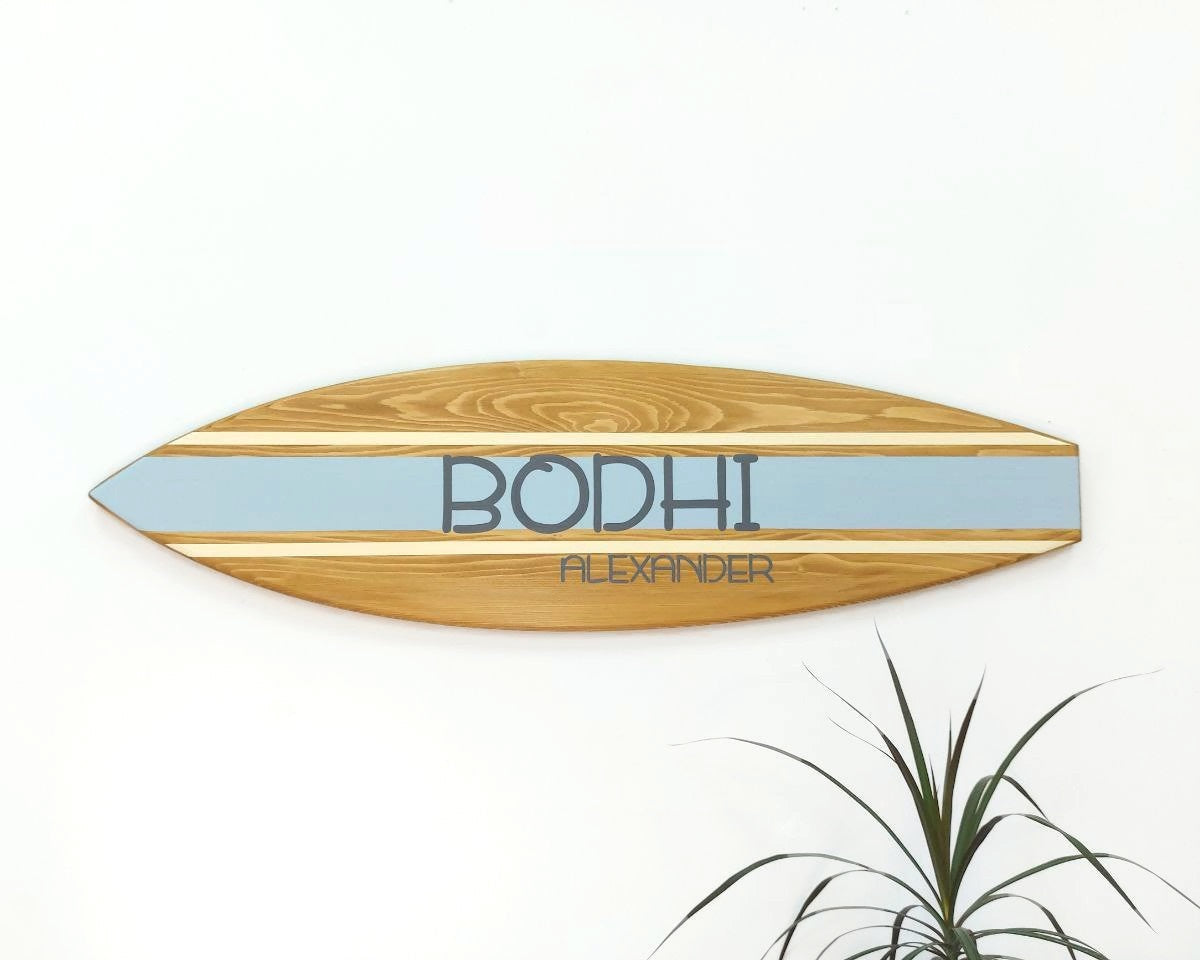 Wooden personalized surfboard sign hanging on wall in nursery