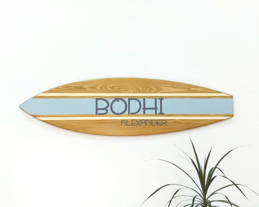 Wooden personalized surfboard sign hanging on wall in nursery