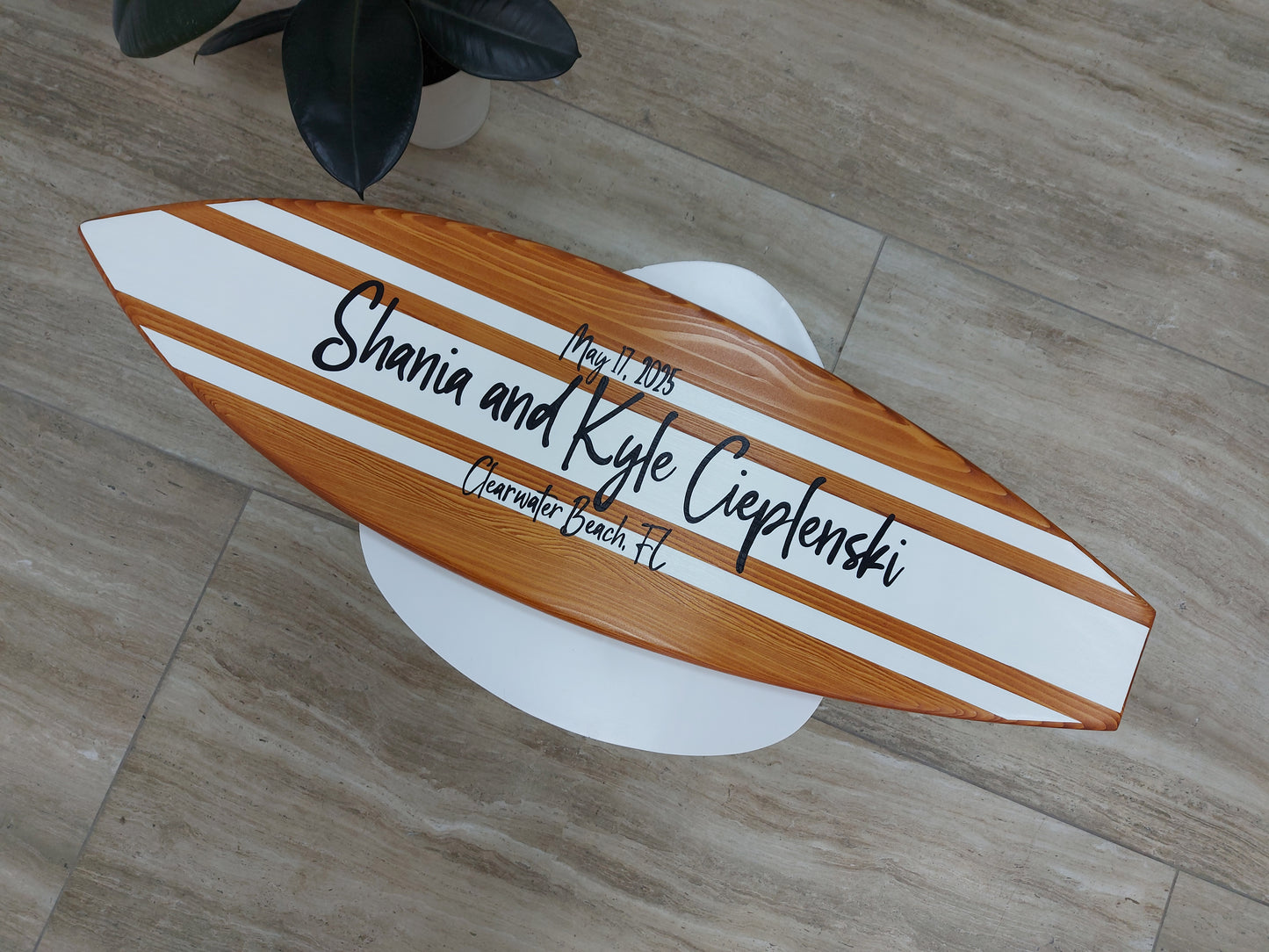 Guests signing wooden surfboard guest book at beach wedding