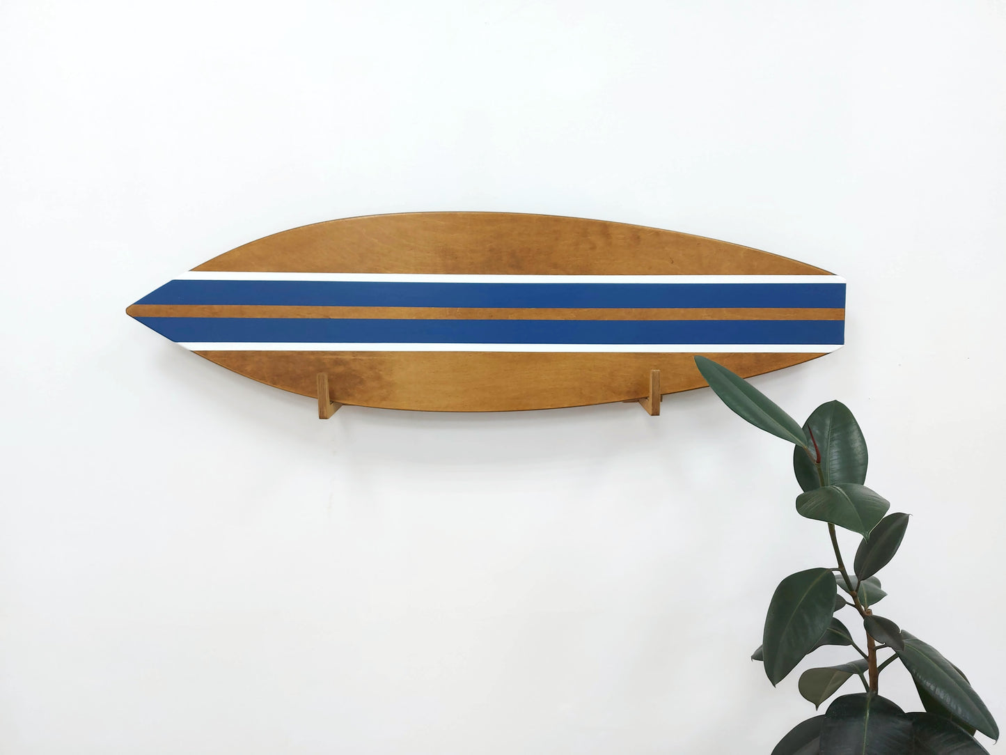 Wooden surfboard with blue and white stripes on a white wall