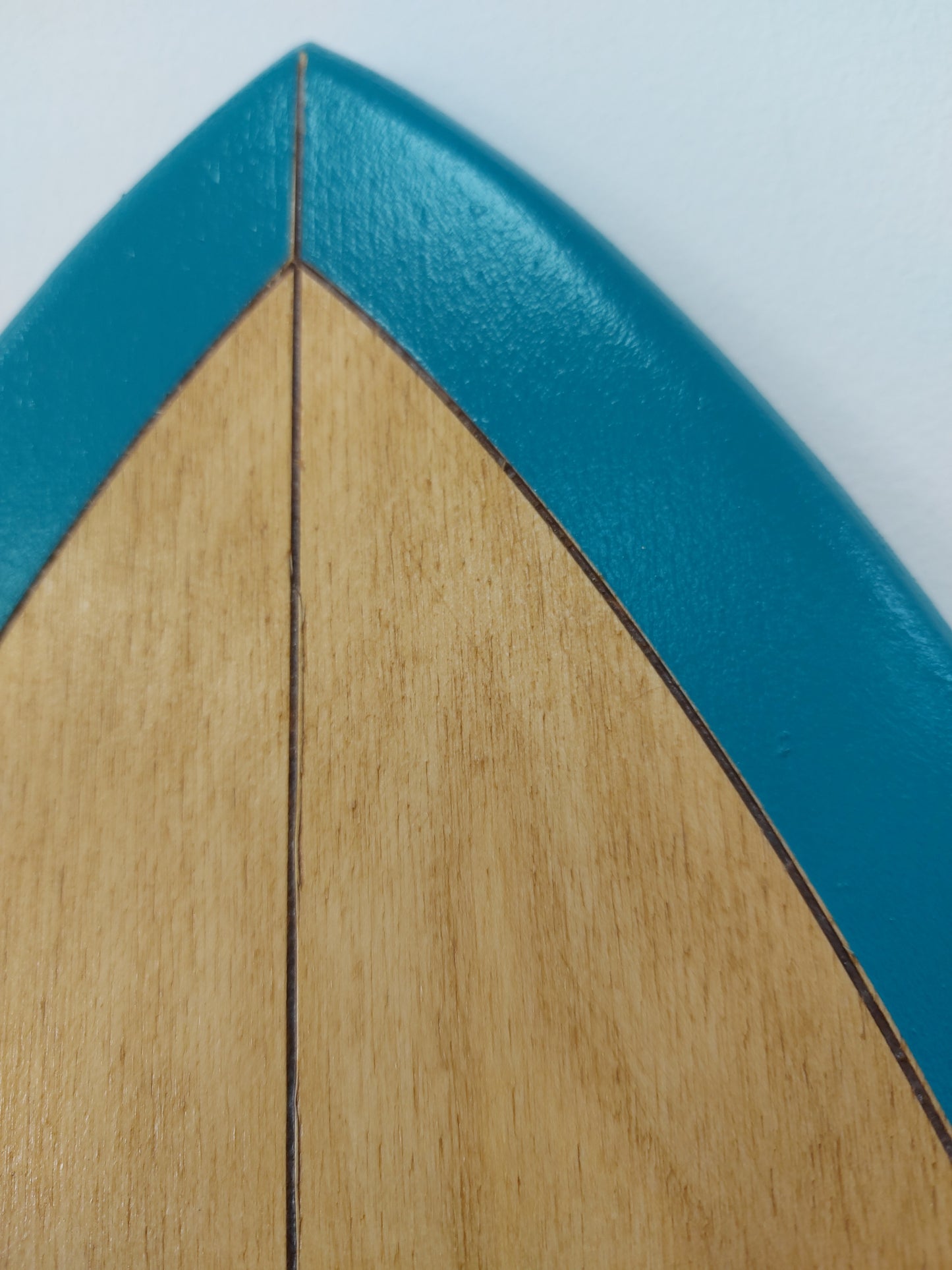 close-up of wooden surfboard wall art texture showing natural grain and teal paint edge