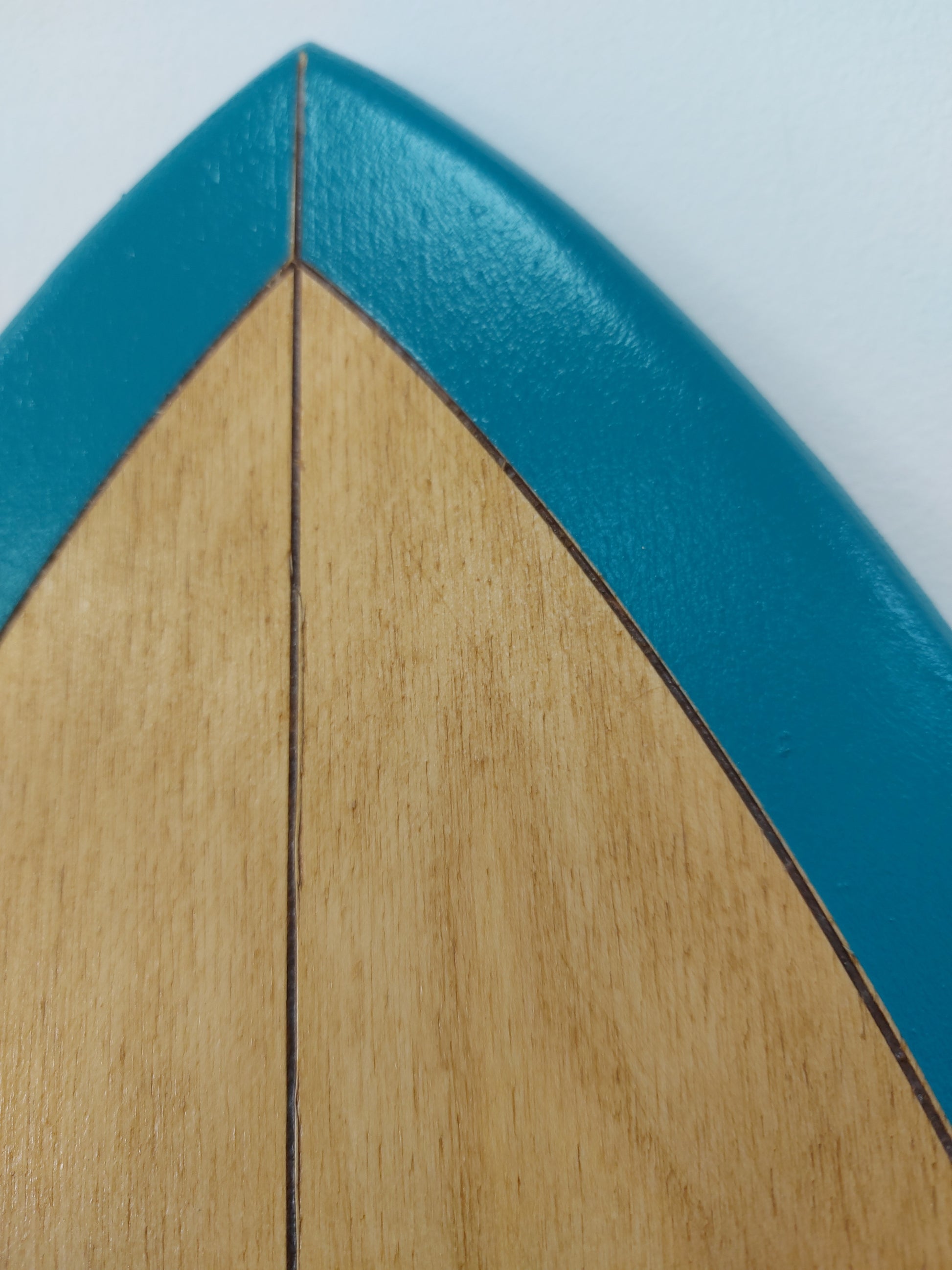 close-up of wooden surfboard wall art texture showing natural grain and teal paint edge
