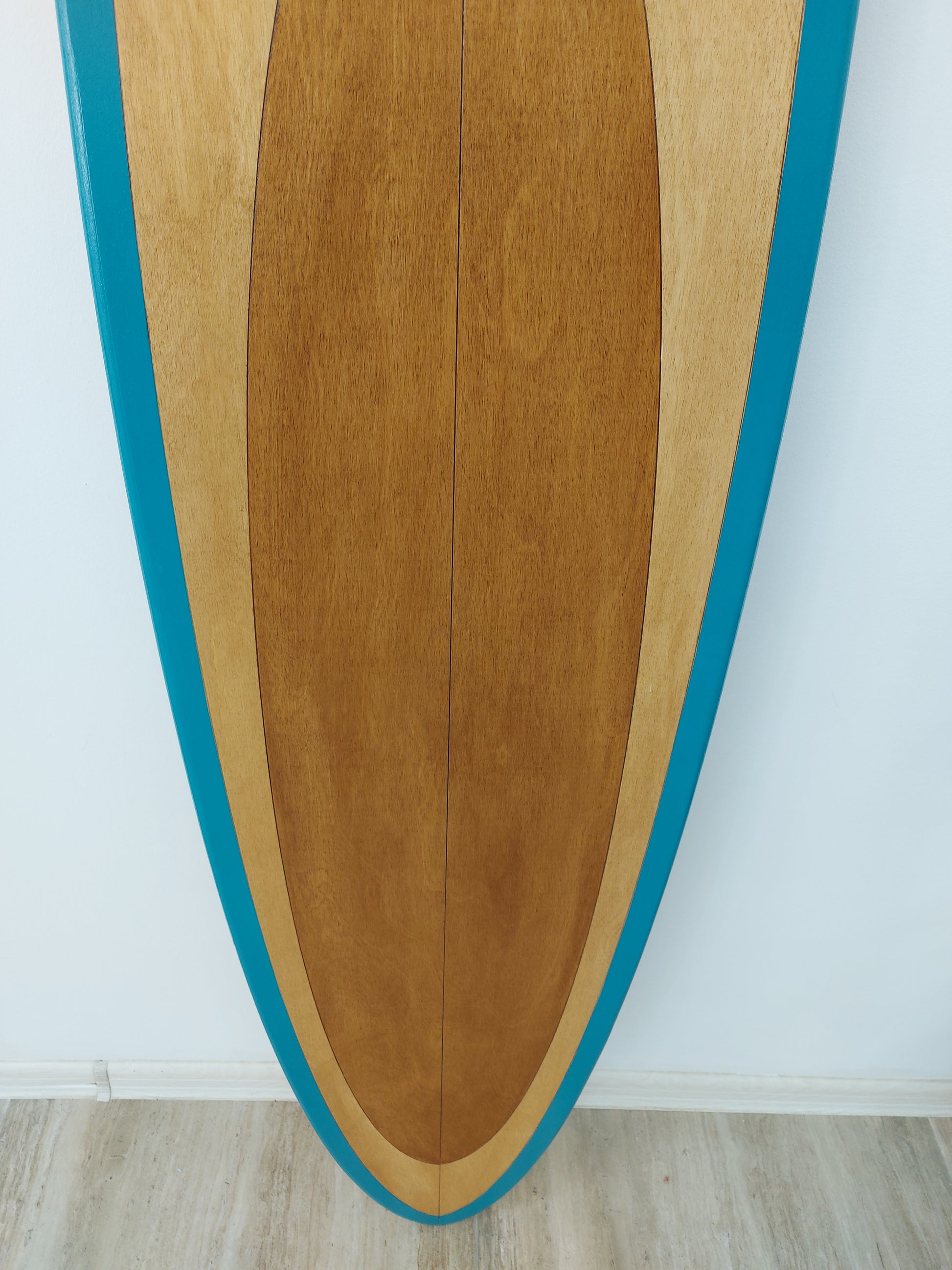 Close-up view of wooden surfboard wall art texture showing natural grain and teal paint edge
